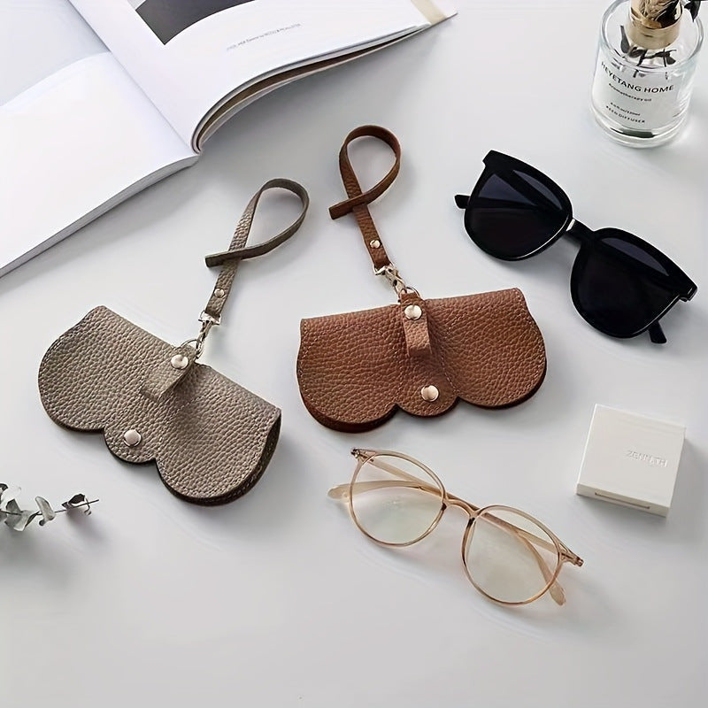 White table with a pair of glasses and sunglasses with 2 of the travel companion clip on glasses holders one is brown the other is khaki or dark grey. A great travel product to use for your glasses case.