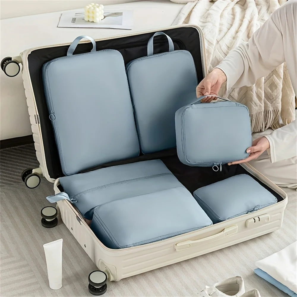 Person packing light blue compression bags into an open suitcase on a bed.