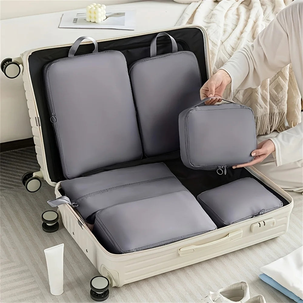 Person organizing gray packing cubes into a suitcase on a bed.