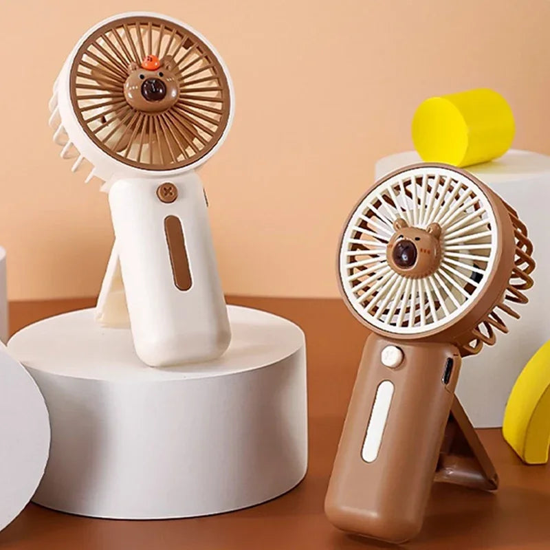 Compact Capybara-themed handheld USB fan one is white the other brown - perfect for travel or theme park use