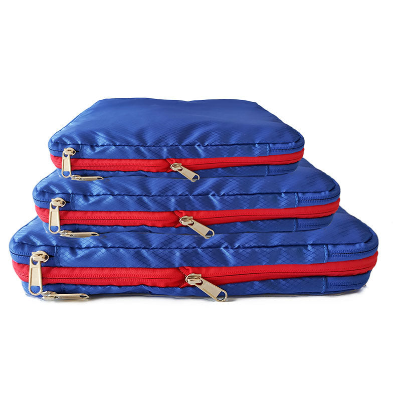 A set of 3 Compression Packing Cubes stacked on top of each other in small, medium and large. They are Bright Blue with red zipper, they are rectangular shaped