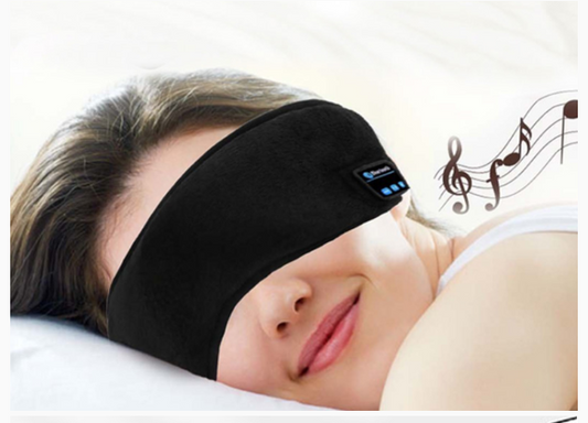 Person wearing a black sleep mask with Bluetooth control on a white pillow.