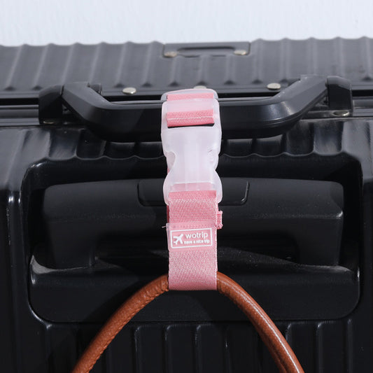 This is a Pink travel strap put through the handle of a black suitcase carry on, holding a handbag.   Showing how the strap can be used. 