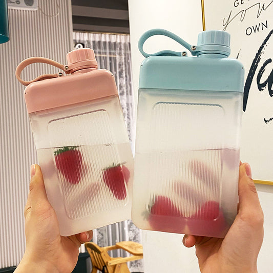 Two hands holding pink and blue flat square water bottles with visible water inside.