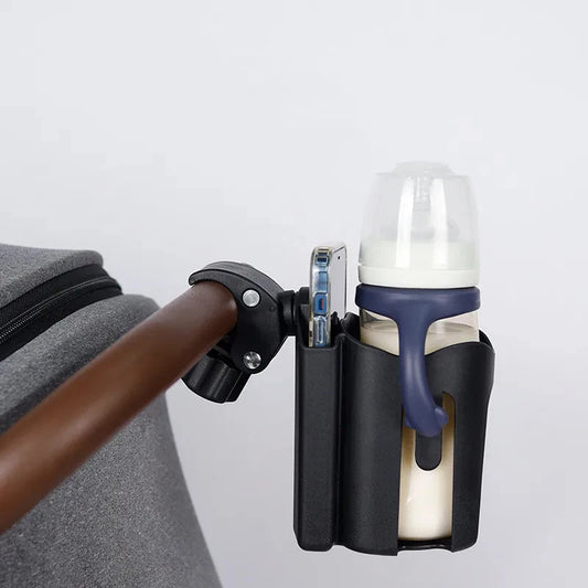 Bottle holder attached to a stroller with a bottle inside on a light gray background