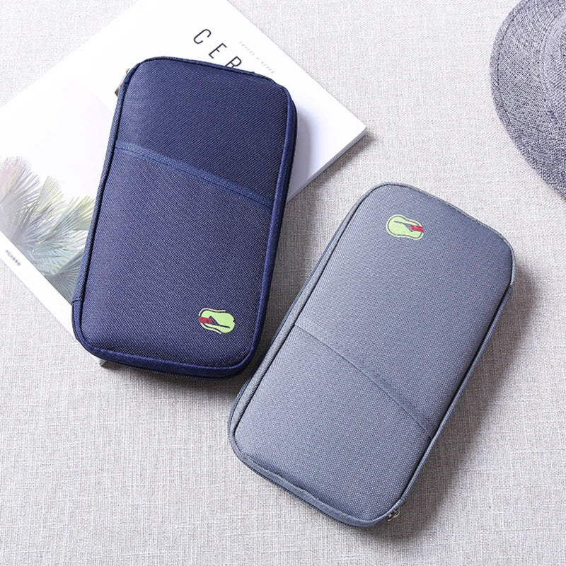 flat lay on a table on top of a book is the navy and grey travel wallets