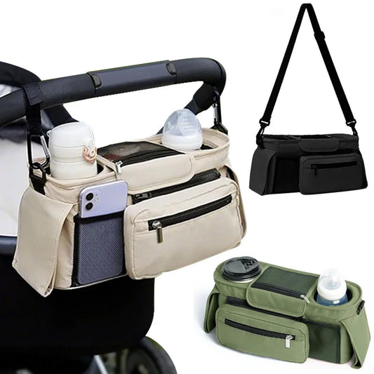 The beige stroller hanging organiser bag is hung on the stroller with the carabiner lips the black and olive bag showing the shoulder strap and the hanging straps.